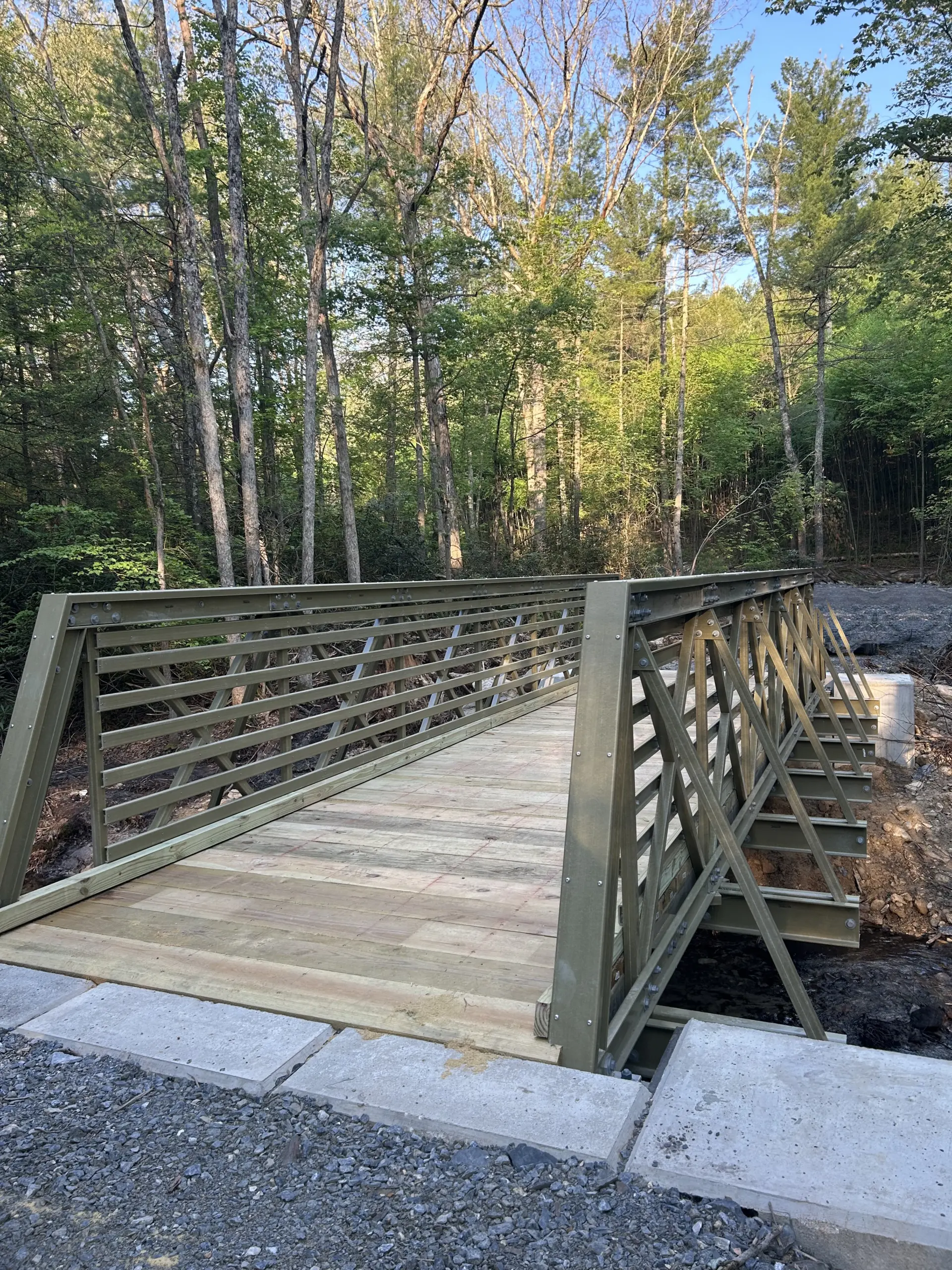 An FRP multi-use truss bridge built over Mountain Creek, surrounded by dense green forest.